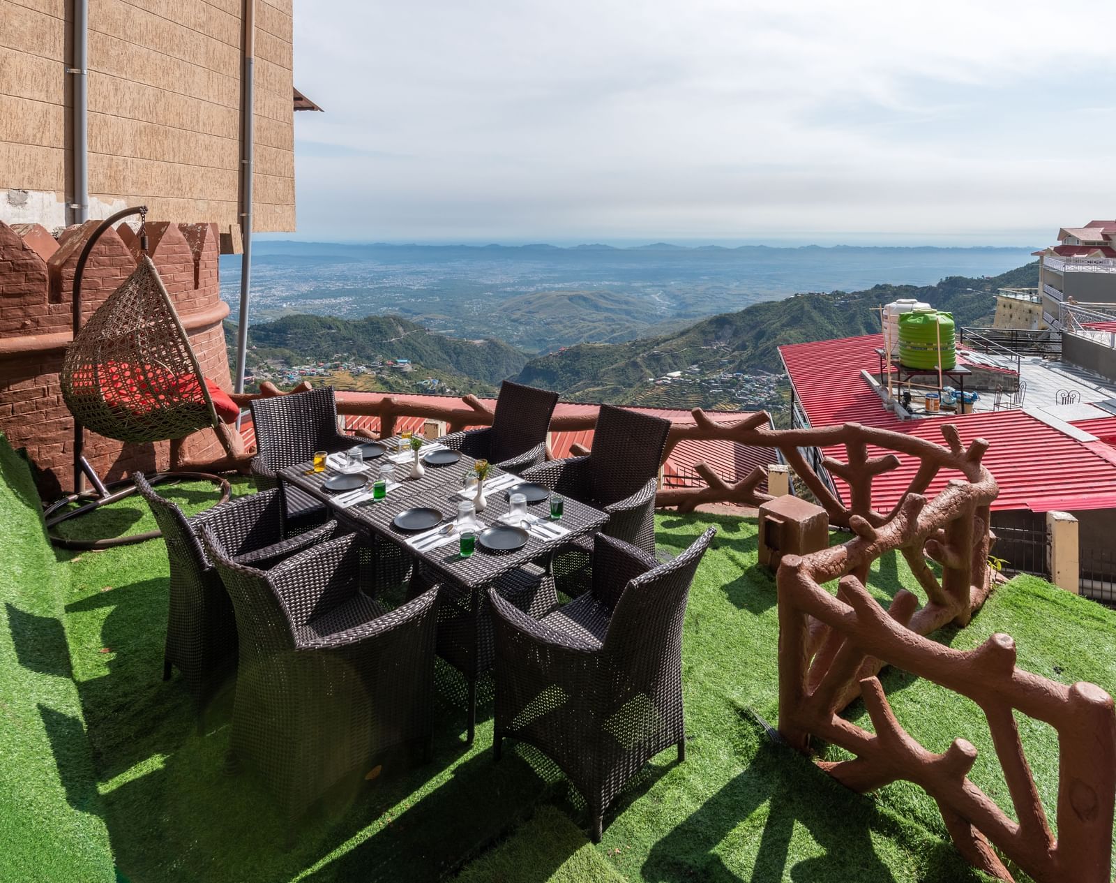 An outdoor dining area with a table and chairs set on a grassy terrace overlooking a scenic mountain landscape | DLS The Pearl